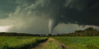 A tornado forming in a rural landscape under dark storm clouds