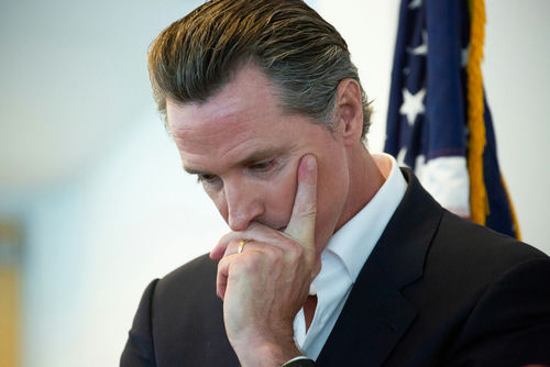 Man in suit thinking with hand on face near a U.S. flag
