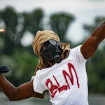 Person in gas mask with Molotov cocktail, BLM shirt.