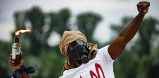 Person in gas mask with Molotov cocktail, BLM shirt.