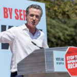 Gavin Newsom speaking at a podium, Stop the Republican Recall.