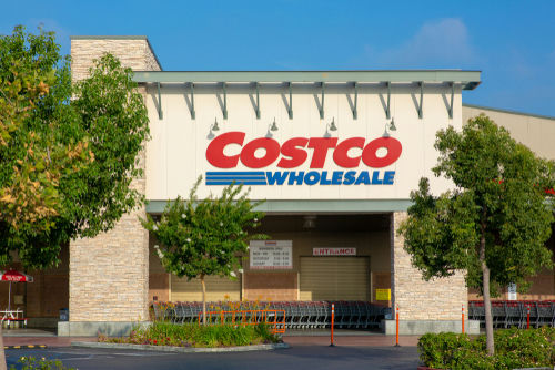 Costco Wholesale storefront with trees and empty shopping carts.