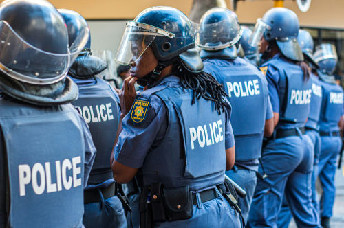 Police officers in riot gear standing in line.