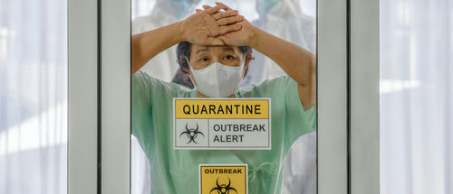 shutterstock_1648211998-1- Person wearing mask behind quarantine glass, outbreak alert sign.