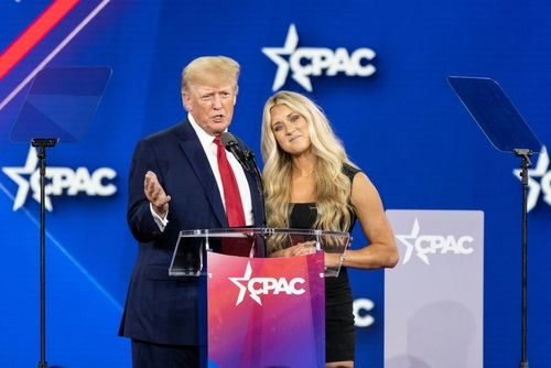 Two people speaking at CPAC event stage.