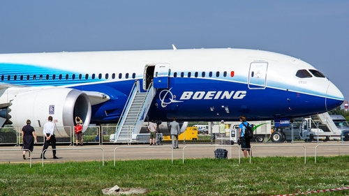 Boeing 787 airplane at an airport with passengers boarding