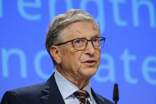 shutterstock_2374506087.jpg A man in a suit speaking at a conference with a blue background
