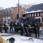 Police officers at a crime scene with a tactical vehicle in a snowy urban area
