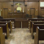 Empty courtroom with wooden benches and judges bench.