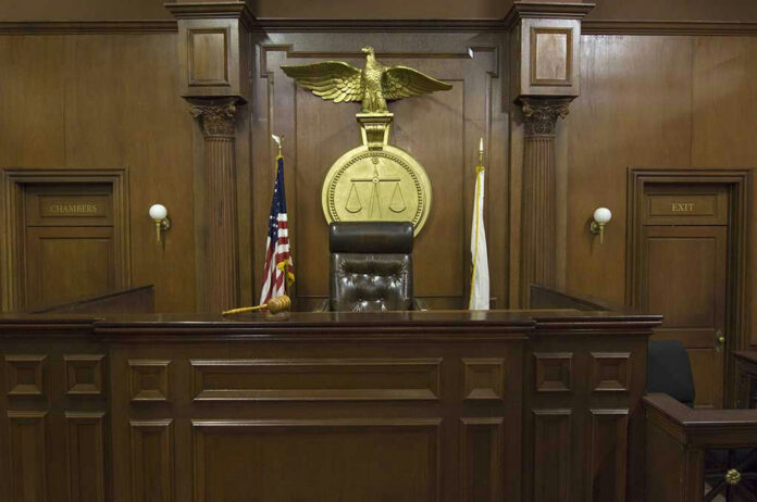 Judges bench in an empty courtroom, scales emblem above.