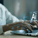 Hands typing on laptop with AI holograms.