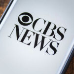 Phone screen showing CBS News logo.