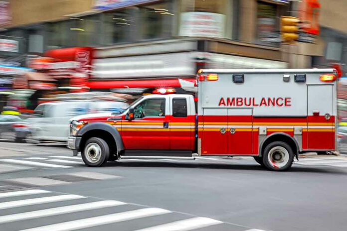 Red ambulance driving quickly through a city street.