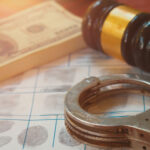 Mob Past Weaponized Against Councilman Handcuffs on fingerprint sheet with gavel and cash