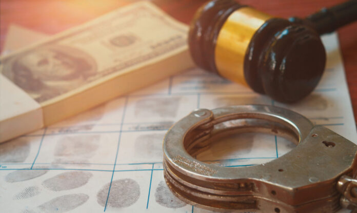 shutterstock2328292487jpg Handcuffs on fingerprint sheet with gavel and cash
