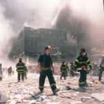 Monster Quake Sparks Tsunami Chaos Firefighters walking through debris near a heavily damaged smoking building