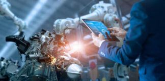 Person using a tablet to monitor robotic machinery.