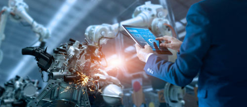 Person using a tablet to monitor robotic machinery.
