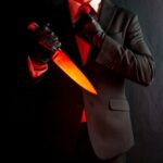 A man in a suit holding a glowing knife against a dark background