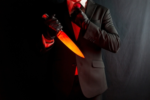 A man in a suit holding a glowing knife against a dark background