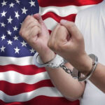 Election Clerk Walks Free—Conviction Stays Person in handcuffs raising clenched fists before a United States flag