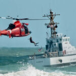 Coast Guard training with helicopter and boat in rough seas.