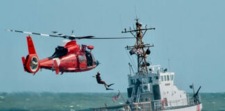 Coast Guard training with helicopter and boat in rough seas.