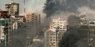 A cityscape showing damaged buildings and thick smoke rising from the ground