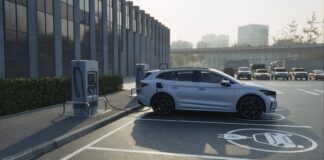A silver electric vehicle charging at a station in a parking lot