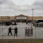 Law enforcement officers and detainees outside a secure detention facility at a Walmart location