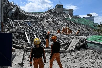 Rescue workers survey collapsed building debris