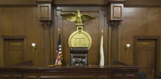 Judges bench in an empty courtroom, scales emblem above.
