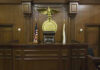 Chilling Custody Plot Alleged Judges bench in an empty courtroom, scales emblem above.