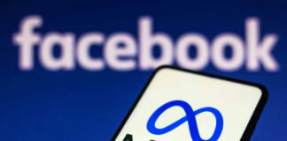 Smartphone displaying Meta logo with Facebook in background.