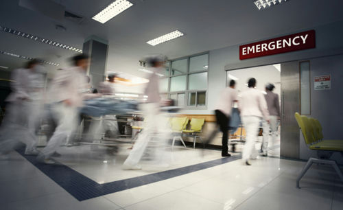 Medical staff rushing patient on stretcher in emergency room.
