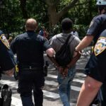 Police escort a handcuffed man across a city street