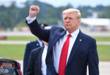 250th Coin Sparks Legal Firestorm A political figure raising a fist in a gesture of confidence during an outdoor event