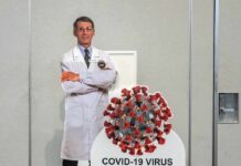 Cardboard cutout of doctor with COVID-19 virus info display