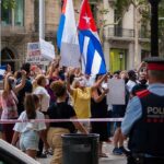 Crowd of protesters holding flags and signs behind police tape