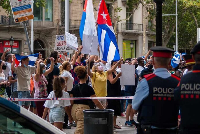 Crowd of protesters holding flags and signs behind police tape