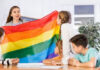 Teacher showing rainbow flag to children in classroom.