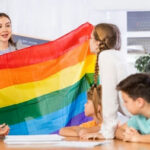 Teacher showing rainbow flag to children in classroom.