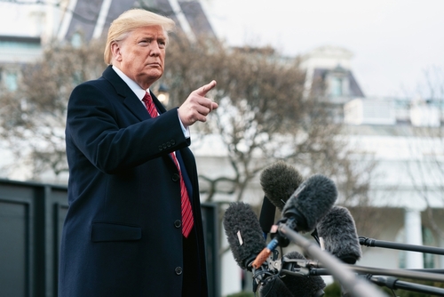 A man in a suit gesturing while speaking at a press conference outside the White House