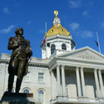 New Hampshire State House with statue in foreground.