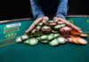 Hands gathering poker chips on a casino table