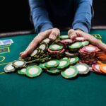 Hands gathering poker chips on a casino table