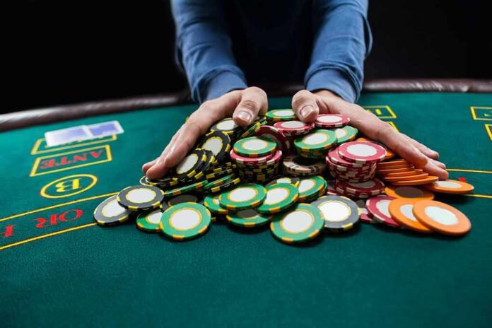 Hands gathering poker chips on a casino table