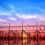 Electrical substation and power lines at sunset with vivid sky and reflections