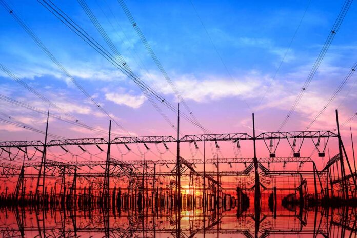 High,Voltage,Power,Grid,,In,The,Sunset Electrical substation and power lines at sunset with vivid sky and reflections