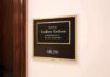 office wall plaque with black and gold nameplate and room number